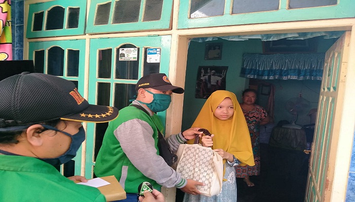 Adi Memberikan Bungkusan ke Anak Yatim (foto: pilihanrakyat.id)