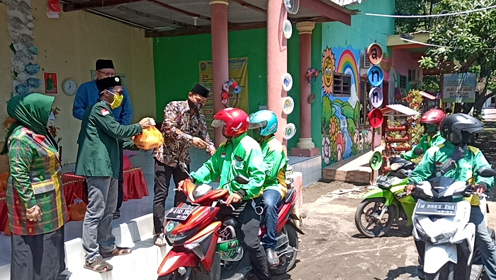 Anisah bersama anaknya membagikan sembako (foto: pilihanrakyat.id)